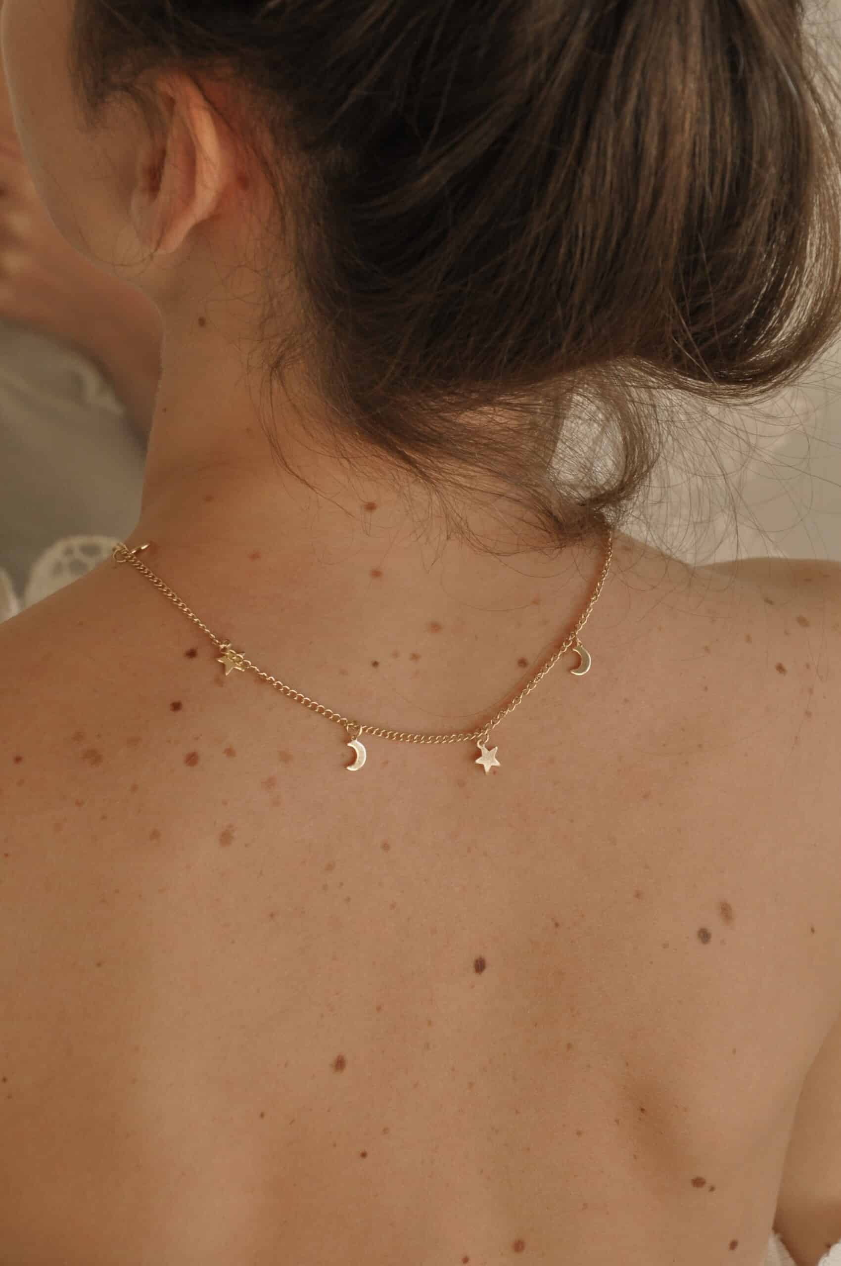 Delicate gold necklace with moon and star charms, perfect for bohemian or everyday style jewelry and adorning the neckline beautifully.