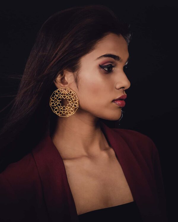 Intricate gold Indian jewelry earring worn by a woman with dark hair and makeup, showcasing traditional fashion accessories from Kurabels.