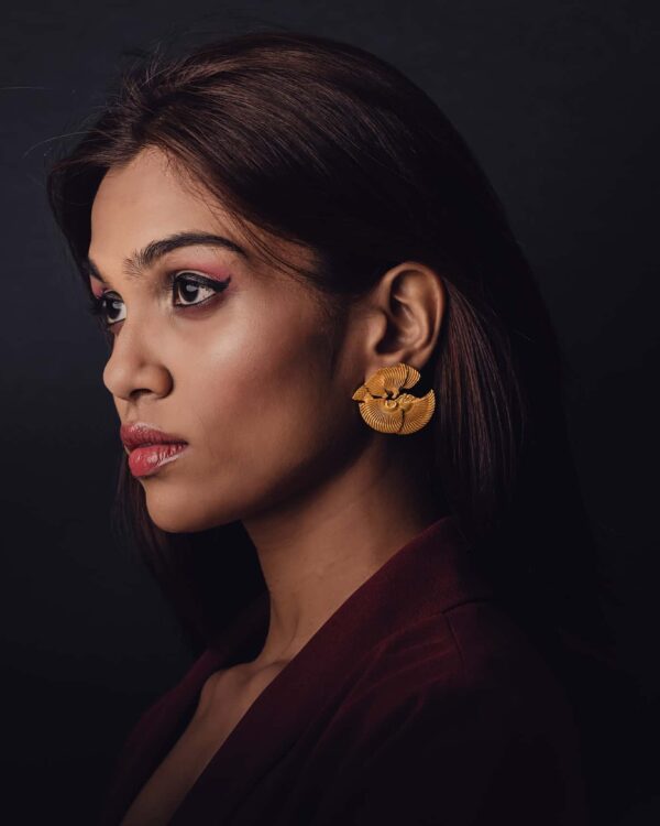 Elegant woman wearing gold Indian jewelry earrings showcasing luxurious designer accessories for traditional festive occasions.
