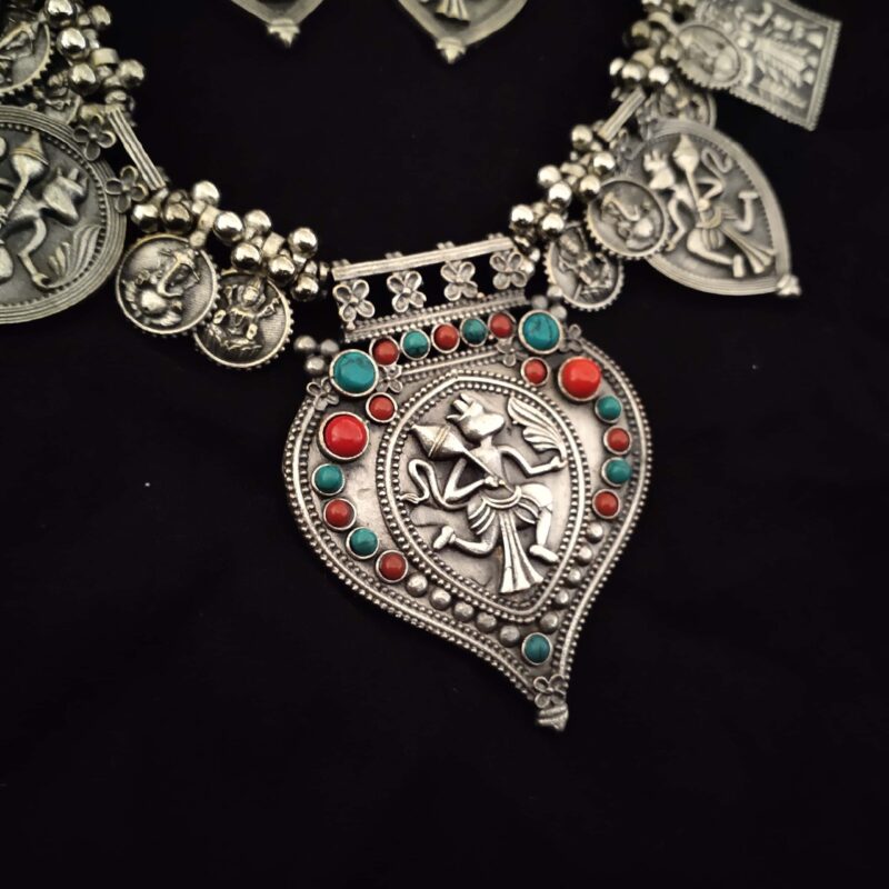 Intricate silver jewelry necklace featuring Lord Vishnu motif with colorful red and turquoise beads, showcasing traditional Indian craftsmanship and ethnic style.