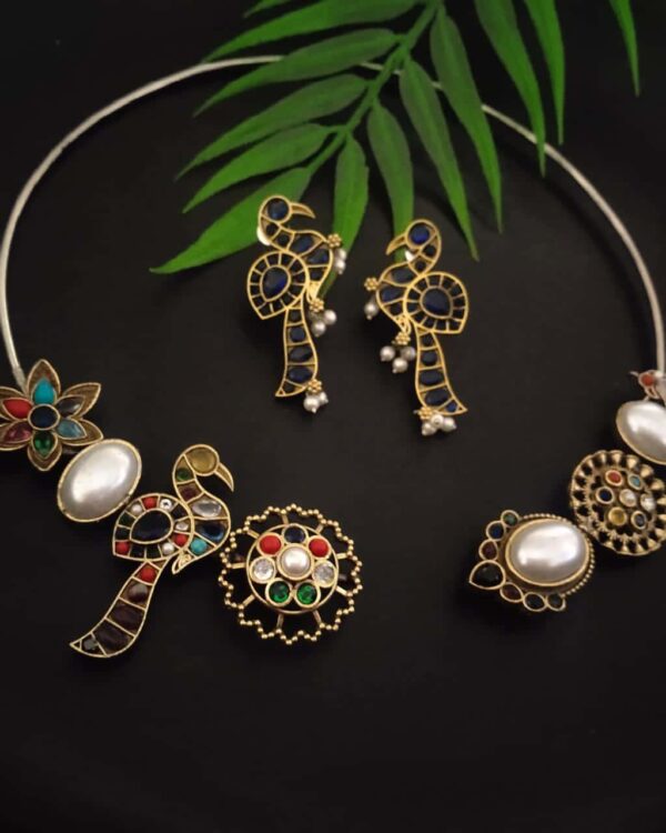 Elegant Indian jewelry set featuring peacock-shaped earrings, floral necklace, and statement rings with vibrant colored stones and pearls, perfect for traditional Indian fashion.