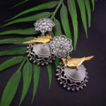 Intricate Indian silver and gold jewelry earrings with floral and bird motifs, embellished with crystals and red stones, perfect for traditional Indian festive occasions.