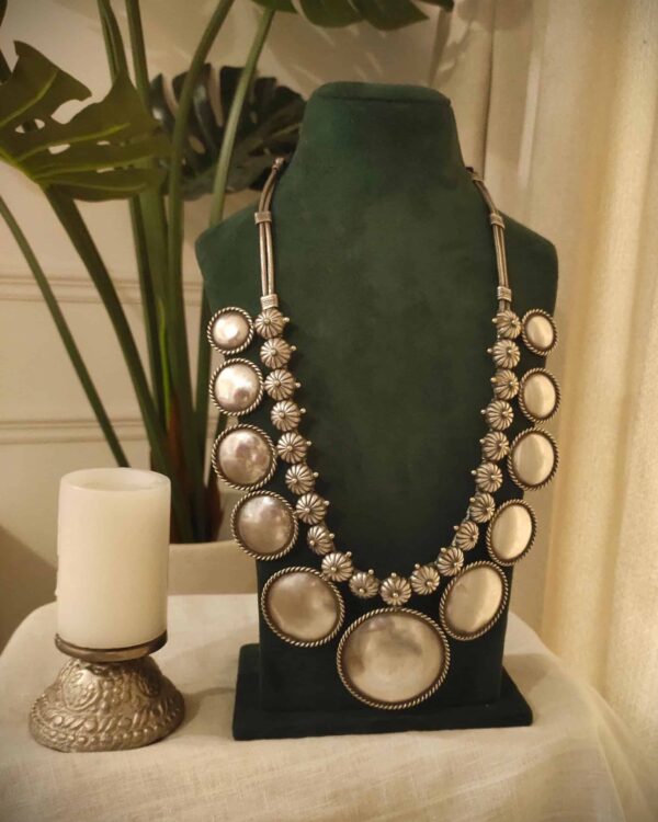 Shimmering silver statement necklace with large circular and floral design elements, perfect for Indian fashion jewelry.