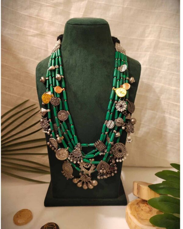 Multi-strand green beaded traditional Indian jewelry necklace with silver and gold-toned charms and intricate designs, perfect for ethnic and festive occasions.