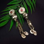 Intricate Indian silver earrings with red gemstone accents, dangling chain details, and traditional motifs, perfect for ethnic fashion and celebrations.