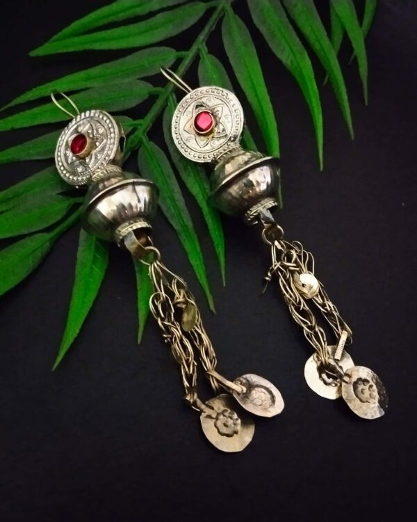 Intricate Indian silver earrings with red gemstone accents, dangling chain details, and traditional motifs, perfect for ethnic fashion and celebrations.