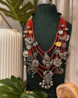 Colorful Indian traditional jewelry with red beads and silver charms on black display bust, showcasing handcrafted ethnic necklace design perfect for Indian fashion jewelry lovers.