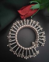 Shiny silver traditional Indian jewelry bracelet with intricate design, placed next to a vibrant red rose on black background for elegant jewelry showcase.
