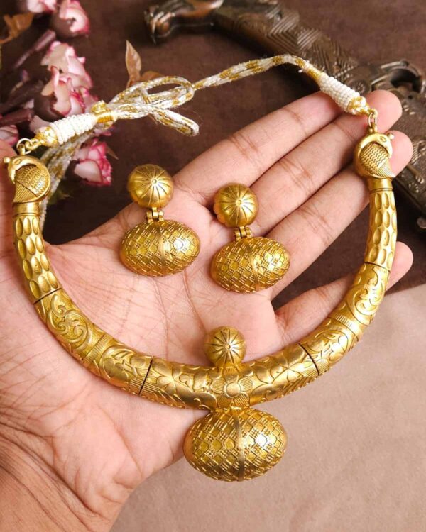 Golden tribal jewelry set including a choker necklace and matching earrings, featuring intricate engraved patterns and traditional design, perfect for Indian festive occasions.