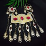 Intricate Indian statement jewelry set with red and blue stones, gold accents, and dangling pearl-like drops, perfect for traditional festive occasions or weddings.