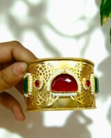 Elegant Indian jewelry bracelet with red, green, and white embellishments, showcasing intricate gold design for traditional festive occasions and stylish wear.