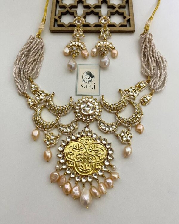 Elegant Indian jewelry set with gold-plated necklace and matching earrings featuring pearl accents, intricate design, perfect for traditional occasions and festive wear.