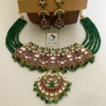 Elegant Indian jewelry set with green beads, gold-plated necklace, and matching chandelier earrings designed for traditional festivities and weddings.