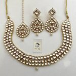 Intricate Indian jewelry set featuring statement necklace and matching earrings with white stones and gold accents, perfect for traditional occasions and festive wear.