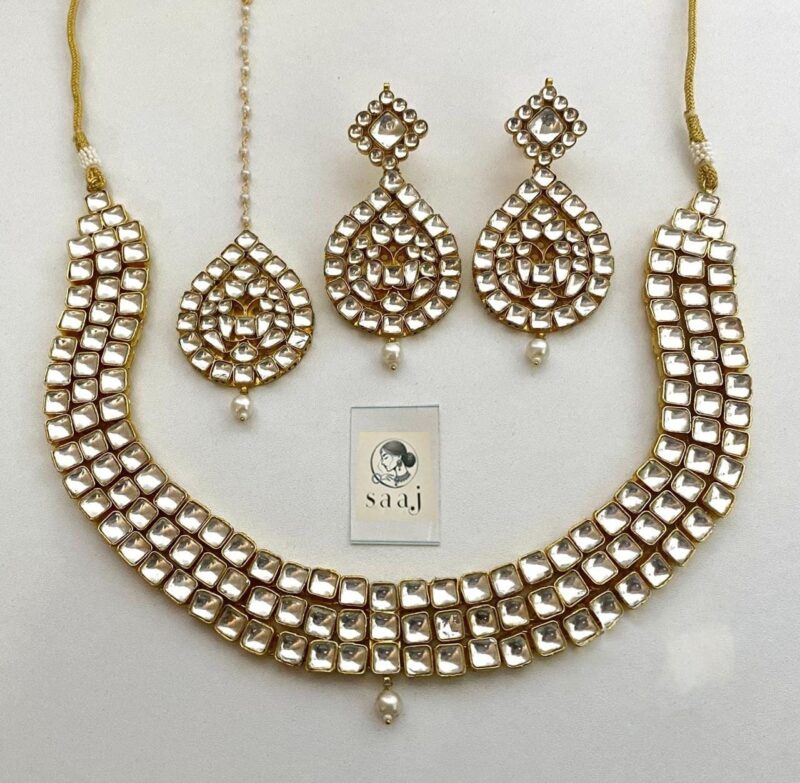 Intricate Indian jewelry set featuring statement necklace and matching earrings with white stones and gold accents, perfect for traditional occasions and festive wear.