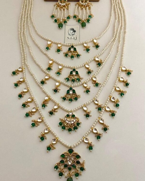 Elegant Indian pearl and green stone jewelry set including layered necklaces and matching earrings, perfect for traditional attire and festive occasions.