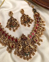 Exquisite gold-plated Indian jewelry set with traditional pendant necklace and matching earrings adorned with red and green gemstones, perfect for festive and special occasions.