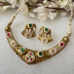 Gold and colored stone traditional Indian jewelry set featuring a necklace and matching earrings with intricate elephant motifs, embellished with pearls and vibrant gemstones. Perfect for festive occasions.