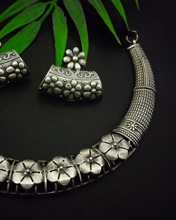 Silver floral jewelry set featuring matching earrings and a statement necklace from Kurabels, showcasing intricate traditional Indian design and craftsmanship.