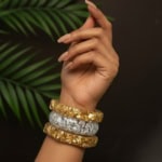 Glamorous Indian fashion jewelry stacked bangles on a feminine wrist, featuring gold and silver textured finishes, perfect for traditional or modern outfits.