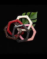 Colorful wooden bangles stacked together with green tropical leaf on black background, perfect for Indian jewelry and fashion accessories.