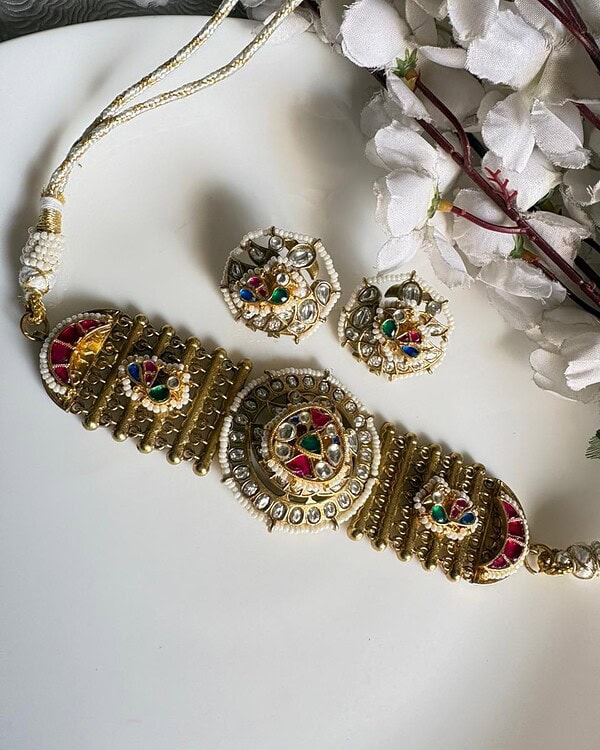 Beautiful Indian traditional jewelry set featuring a statement necklace and matching earrings with colorful stones, pearls, and intricate gold detailing, perfect for festive or special occasions.