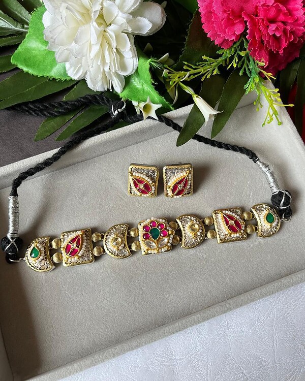 Elegant Indian jewelry set including a choker necklace and matching earrings with intricate gold plating, colorful stones, and pearl accents, perfect for traditional and festive occasions.