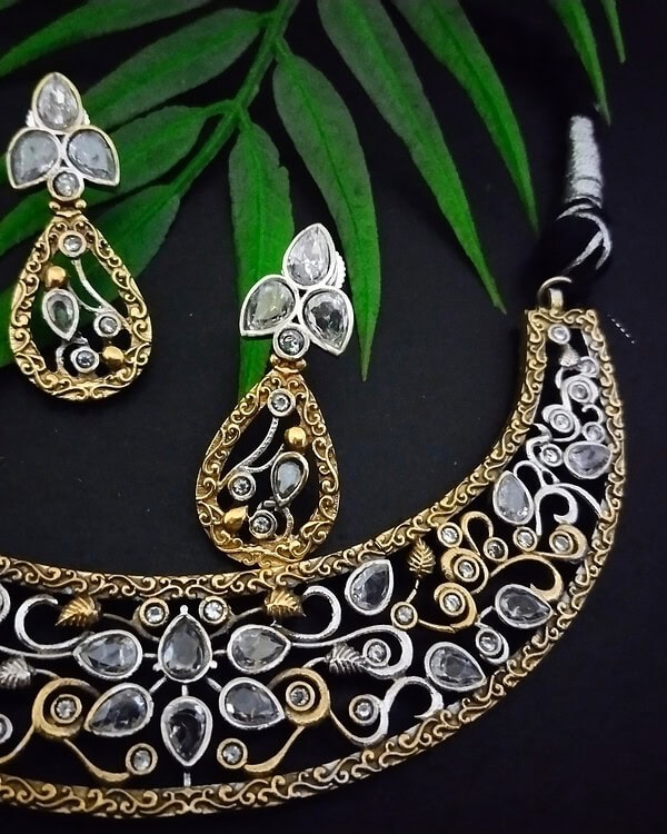 Elegant Indian jewelry set featuring gold and silver necklace with matching earrings, adorned with intricate designs and sparkling gemstones, perfect for traditional festive occasions.