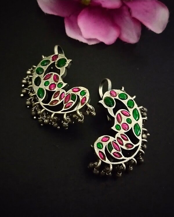 Intricate silver earrings with pink and green stones, featuring traditional Indian design and hanging bell details, perfect for festive or cultural occasions.