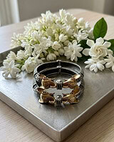 Beautiful gold and silver bracelet featuring intricate animal motifs, displayed on a neutral surface with a backdrop of fresh white flowers, perfect for Indian fashion jewelry lovers.
